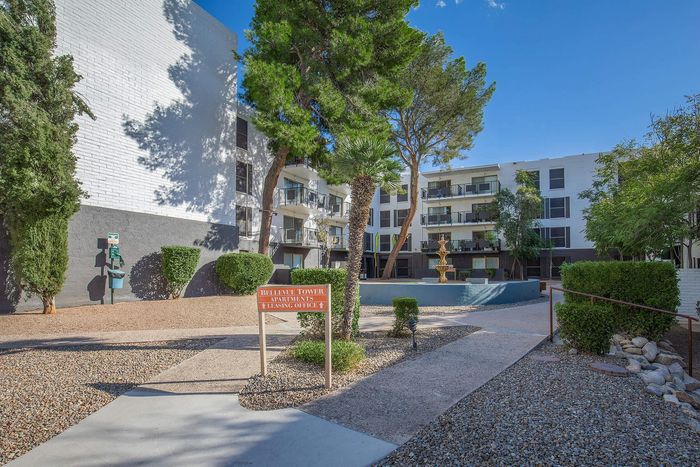 Charming Bellevue Tower Apartments exterior with lush greenery and a serene central fountain, offering a welcoming atmosphere.