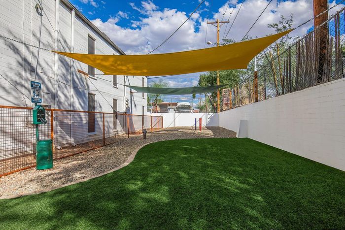 Charming outdoor area with lush green grass and colorful sun shades, perfect for relaxation in a pet-friendly community.