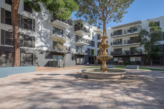 Charming apartment complex with modern balconies and a central courtyard featuring an elegant tiered fountain.