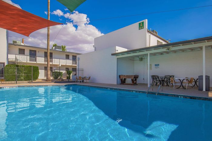 Vibrant apartment complex pool area featuring crystal-clear blue water, stylish poolside furniture, and a recreational foosball table under a shaded patio.