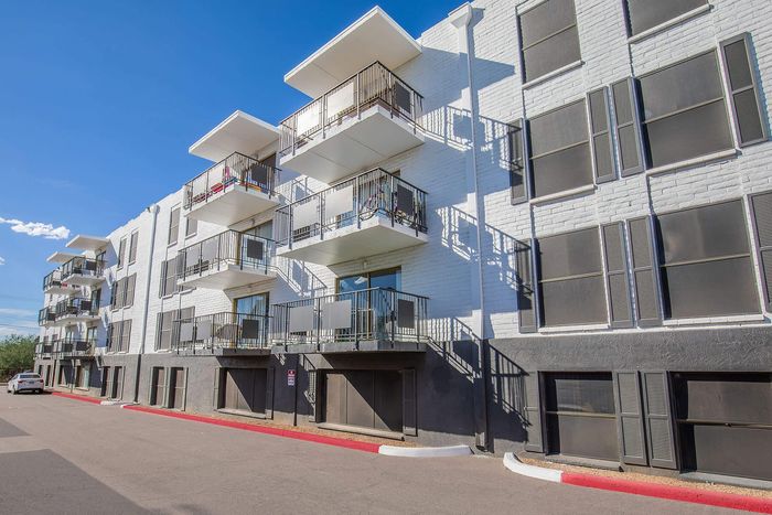 Modern apartment building with charming balconies under a clear blue sky, offering contemporary urban living.