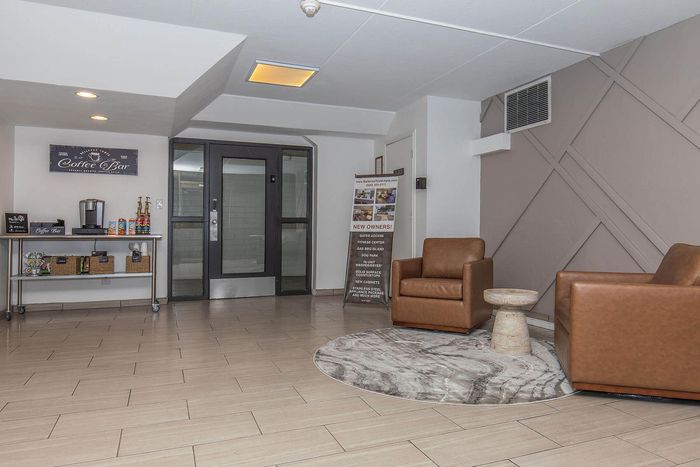 Inviting apartment lobby featuring stylish leather chairs, sleek tile flooring, and a modern coffee bar area.