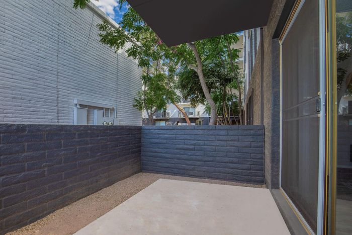 Charming apartment patio with privacy walls and lush green views, perfect for outdoor relaxation.