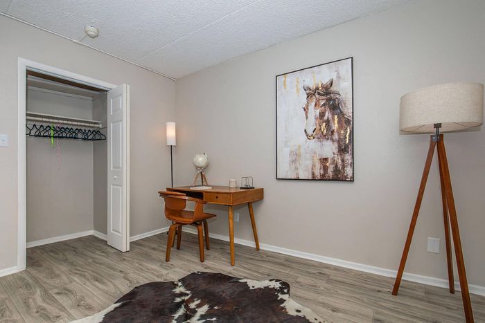 Chic home office with a wooden desk, globe, and stylish decor, featuring a modern floor lamp and elegant artwork. Inviting space for productivity and inspiration.