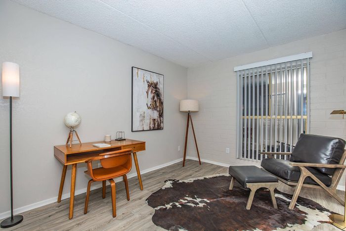 Chic home office with sleek leather armchair, modern wooden desk, and ambient lighting creating a cozy workspace atmosphere.