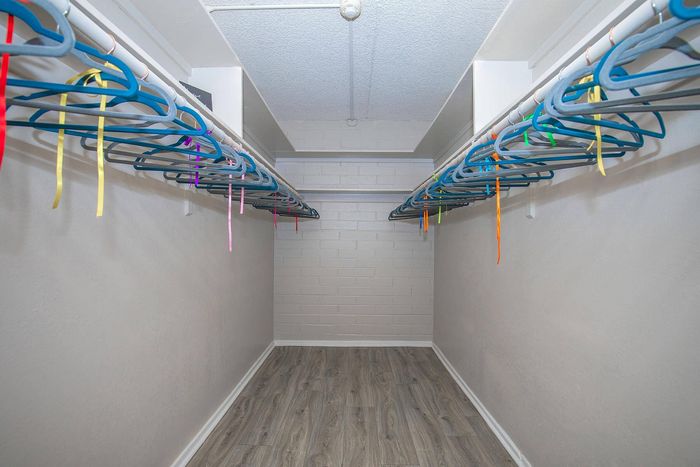 Spacious walk-in closet with stylish wooden flooring and vibrant hangers, offering ample storage for modern living.