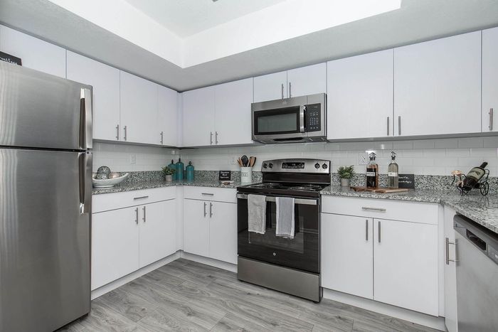 Modern kitchen with sleek stainless steel appliances, spacious granite countertops, and elegant white cabinetry.