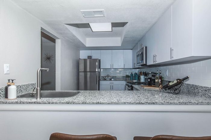 Modern kitchen with sleek granite countertops, stainless steel appliances, and elegant white cabinetry.