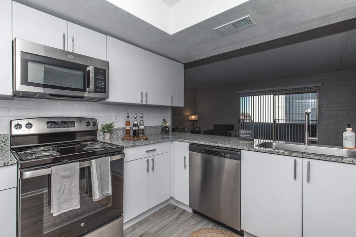 Modern kitchen with sleek stainless steel appliances, granite countertops, and stylish white cabinetry.