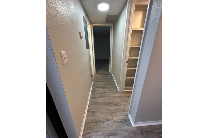 Bright and welcoming hallway featuring sleek wood flooring, recessed lighting, and built-in storage for a modern apartment aesthetic.