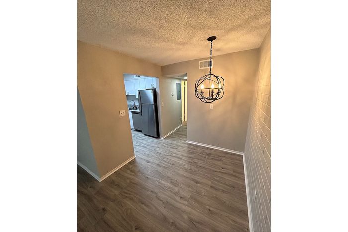 Modern apartment interior with elegant pendant lighting, sleek stainless steel appliances, and chic laminate flooring.