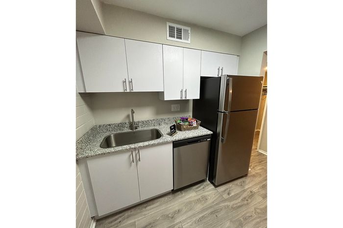 Modern kitchen featuring sleek white cabinets, granite countertops, and stainless steel appliances for a contemporary living experience.