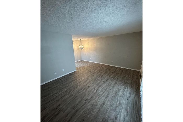 Spacious living area with elegant wooden flooring and modern lighting, perfect for relaxation and entertainment.