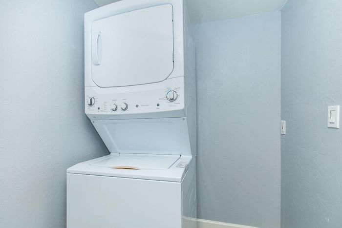 Bright laundry room featuring a sleek, modern stacked washer and dryer set against a clean, neutral wall.