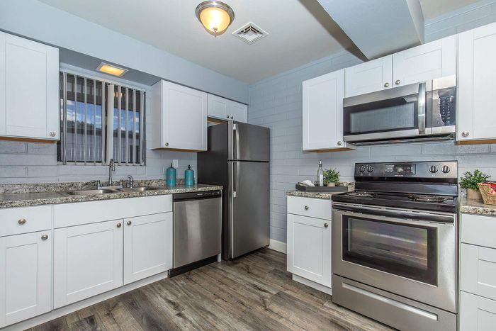 Modern kitchen with sleek stainless steel appliances, white cabinetry, and stylish granite countertops, perfect for culinary enthusiasts.