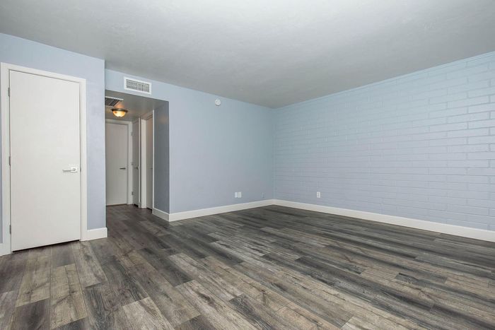 Modern apartment interior featuring sleek hardwood flooring, neutral blue walls, and clean architectural lines.