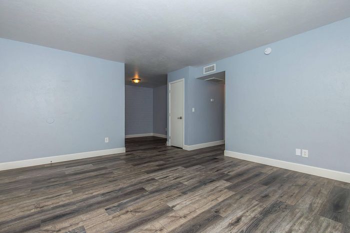 Elegant living area with modern wood flooring and soft blue walls, offering a serene and contemporary atmosphere.