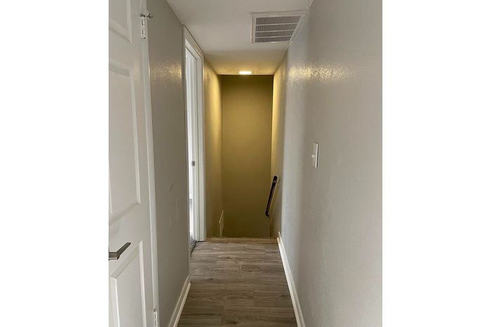Bright hallway with sleek hardwood flooring, leading to a cozy staircase. Modern and inviting design.
