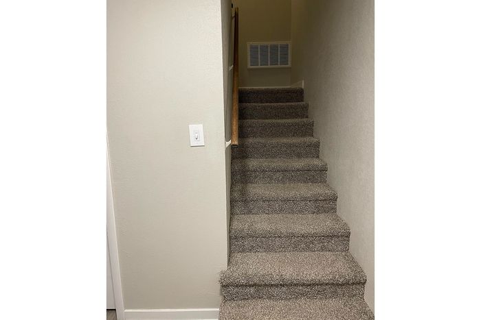 Modern staircase with plush carpeting and sleek wooden banister in a cozy home setting.