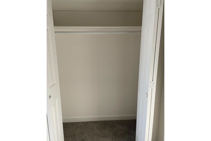 Bright and spacious closet with double doors, ideal for organized storage in a modern apartment.