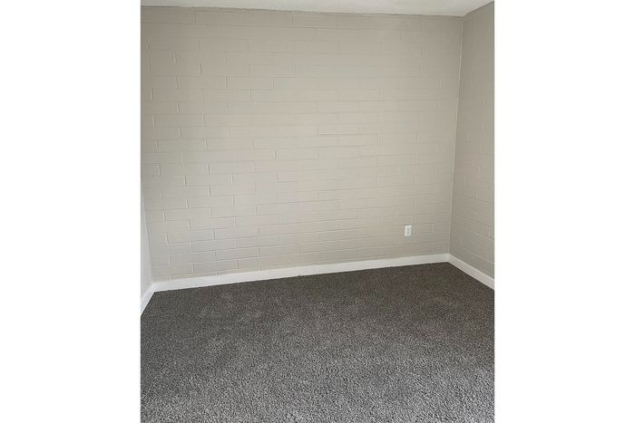 Bright and clean corner space with soft carpet flooring and a modern textured wall, perfect for personalization.
