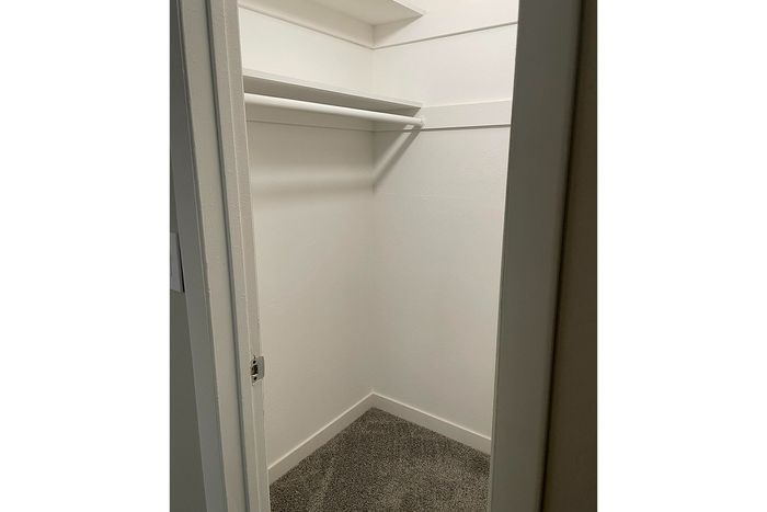 Spacious walk-in closet with white walls and shelving, perfect for organizing your wardrobe.