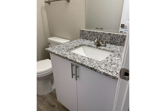 Sleek bathroom with granite countertop, modern sink fixtures, and chic flooring.