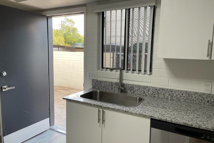 Modern kitchen with granite countertops, sleek faucet, and access to a bright patio area.
