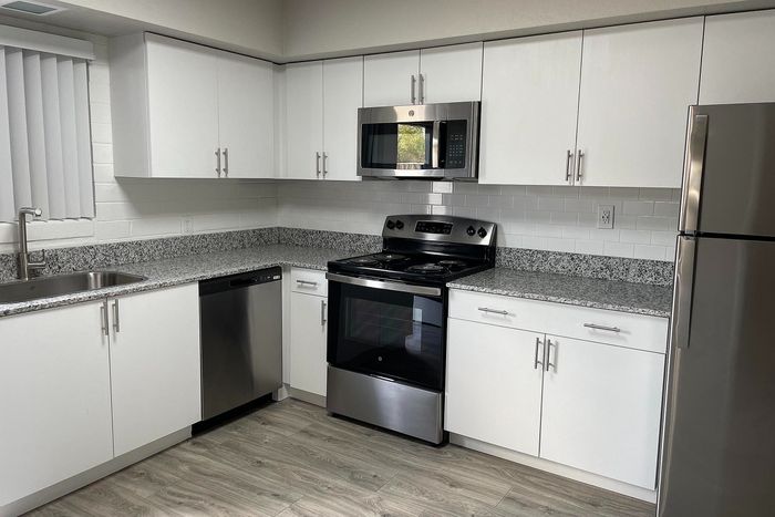 Modern kitchen with sleek stainless steel appliances, granite countertops, and contemporary white cabinetry.