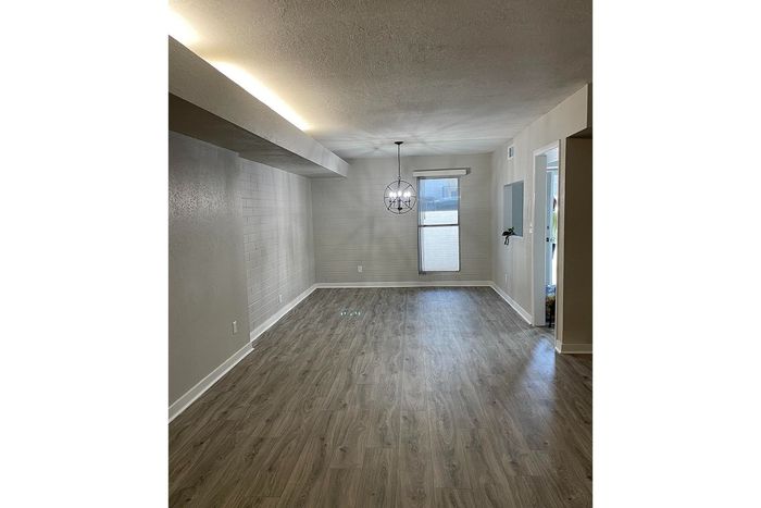 Bright and modern living space with elegant wood flooring, chic light fixture, and an inviting window view.