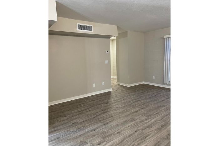 Spacious room with elegant laminate flooring, featuring neutral wall colors and natural light from large windows. Perfect for modern living.