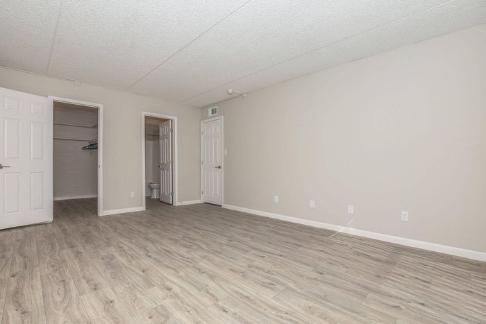 Inviting apartment room featuring durable laminate flooring, minimalist beige walls, and convenient closet space.