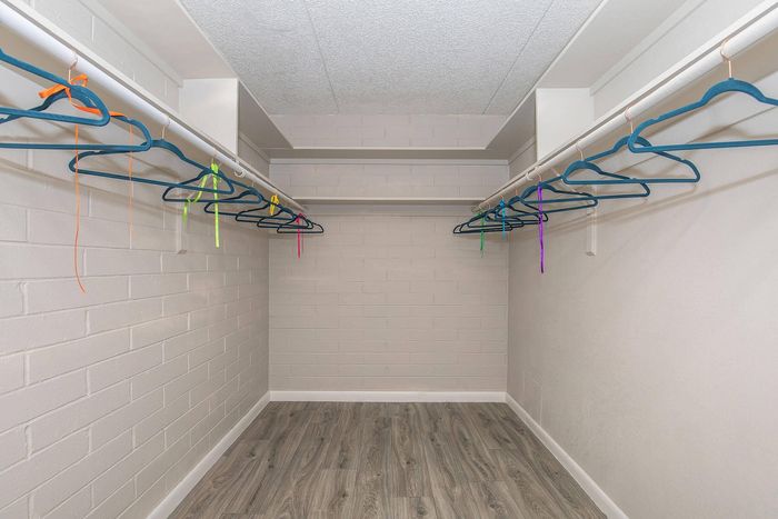 Spacious walk-in closet with stylish wooden floor and ample hanging space featuring colorful hangers.