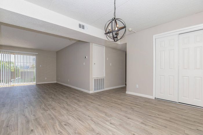 Bright and airy living space with modern wood flooring, a stylish chandelier, and large sliding doors leading to a private balcony.