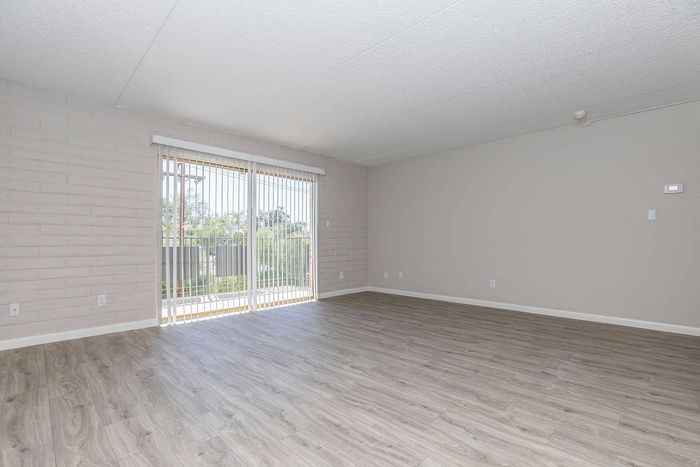 Bright, spacious living room with elegant wood flooring and floor-to-ceiling windows offering a scenic view.