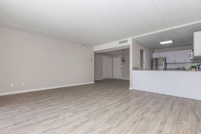 Modern apartment interior with elegant wood flooring, open living area, and sleek kitchen design.