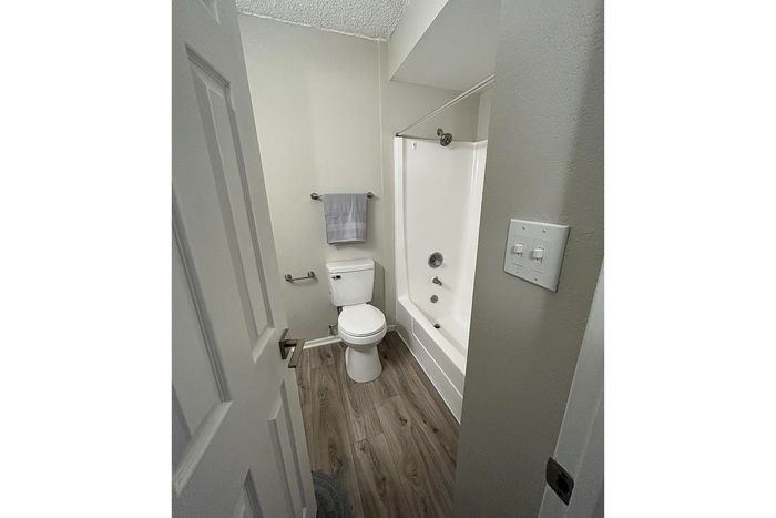 Modern bathroom featuring elegant wood flooring, a sleek white bathtub, and stylish fixtures.
