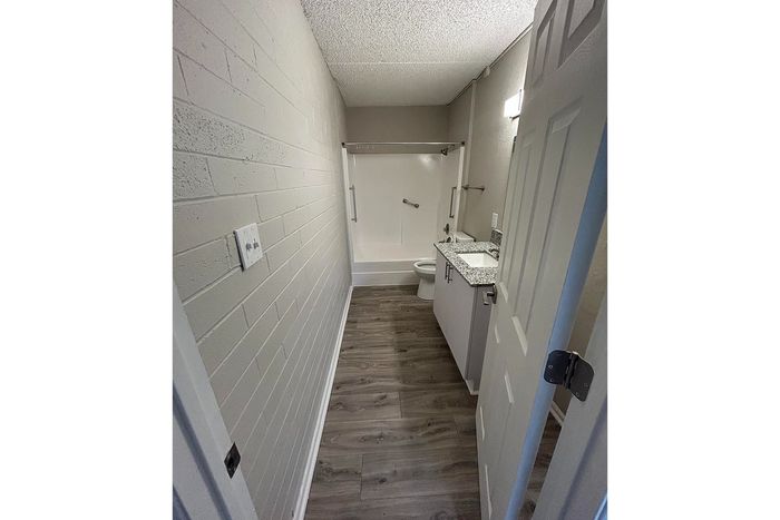 Contemporary bathroom featuring sleek granite countertops, elegant fixtures, and a modern tiled shower area with stylish wood-look flooring.
