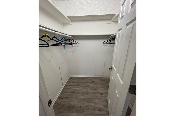 Spacious walk-in closet with elegant wood flooring and ample hanging space, perfect for organizing your wardrobe.