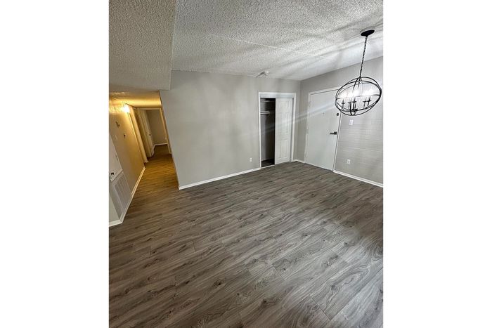 Modern apartment interior with elegant wood flooring, inviting hallway, and stylish chandelier lighting.