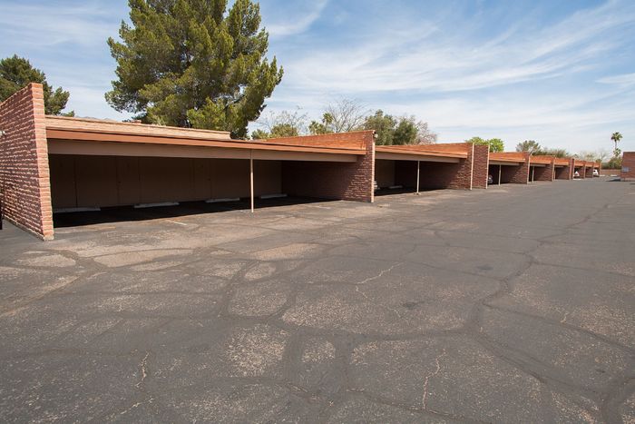 Charming outdoor parking area with brick structures and lush greenery, offering convenient and secure vehicle storage.