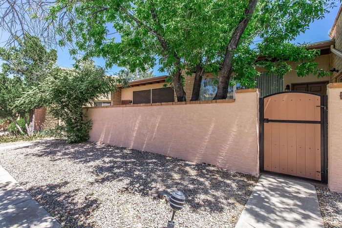 Charming suburban home with a private courtyard bordered by lush greenery and a picturesque wooden gate.