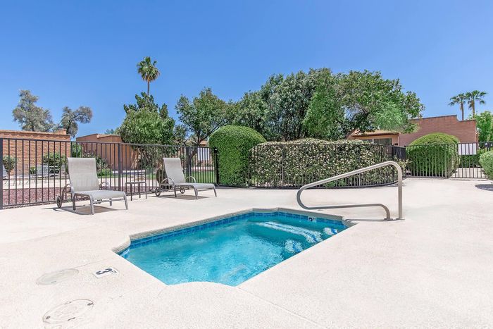 Inviting outdoor space with a sparkling jacuzzi, surrounded by lush greenery and comfortable lounge chairs, perfect for relaxation.
