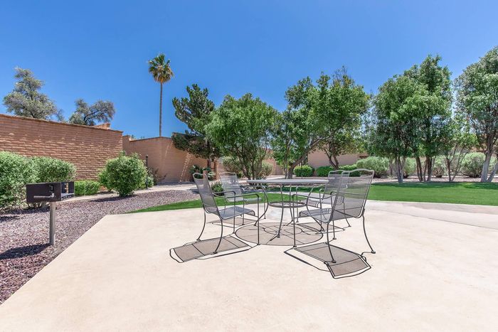 Inviting outdoor patio area with modern seating and lush greenery, ideal for relaxing and entertaining under clear blue skies.