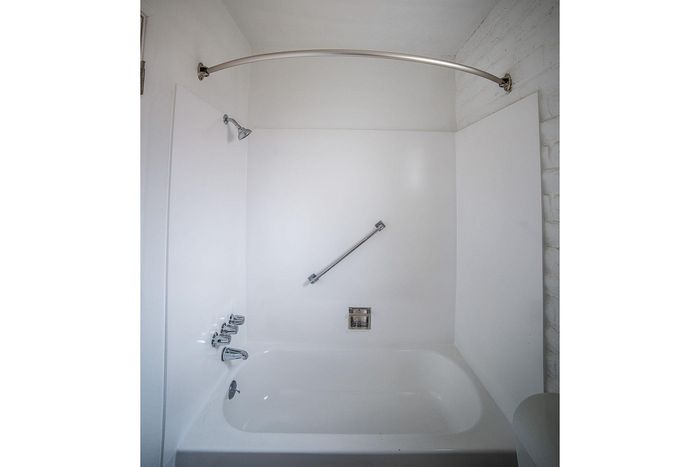 Modern bathroom with sleek white bathtub, elegant curved shower rod, and polished chrome fixtures.