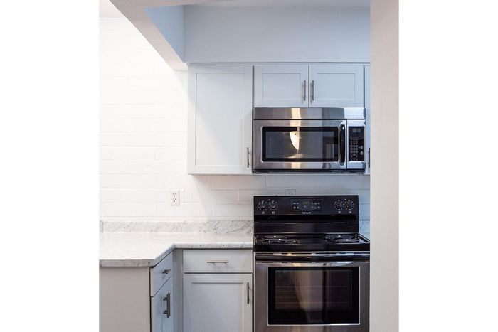 Modern kitchen with sleek stainless steel appliances, white cabinetry, and polished marble countertops.