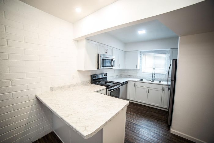 Bright and modern kitchen with sleek white cabinetry, stainless steel appliances, and elegant marble countertops.