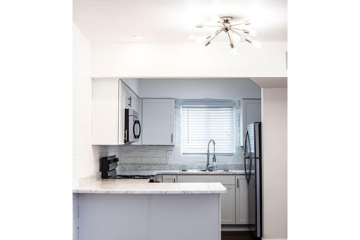 Modern kitchen with sleek white cabinets, stainless steel appliances, and elegant lighting.
