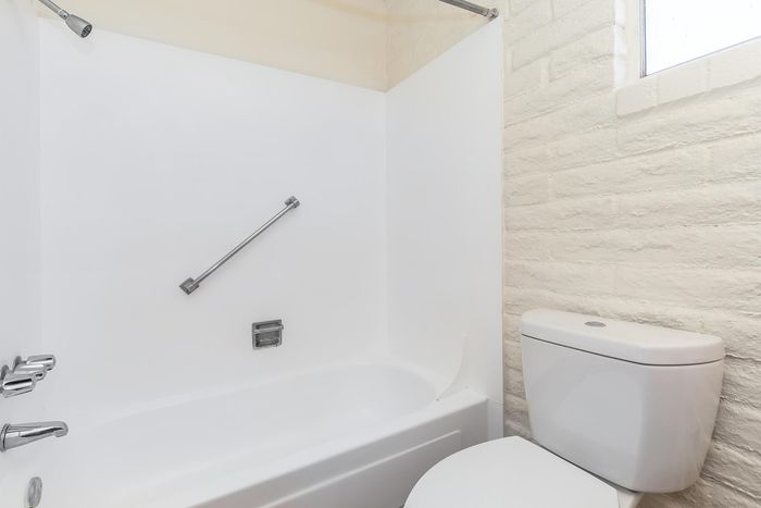 Bright and modern bathroom featuring a sleek bathtub, pristine white tiles, and a convenient showerhead.