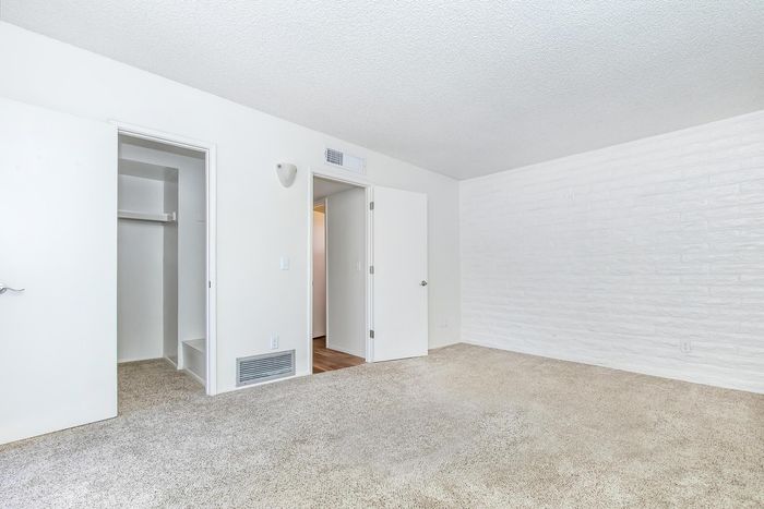 Bright bedroom showcasing plush carpet, built-in closet, and modern white walls.